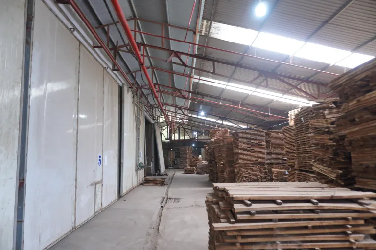 Corridor alongside a row of drying kiln doors with stacked timber