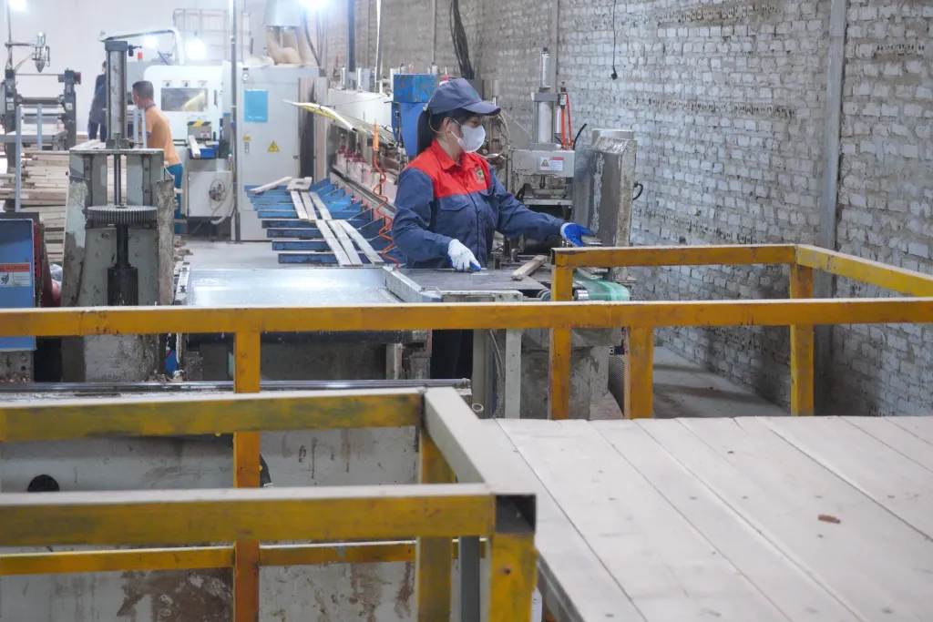 Operator at a finger-joint machine behind yellow guard rails