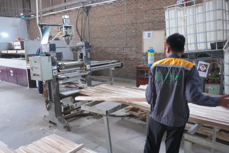 Operator feeding wood strips through a glue spreader