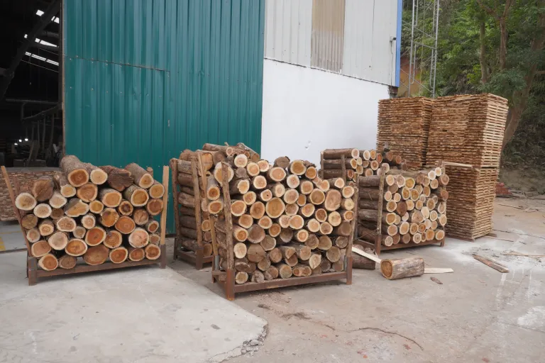 Short acacia logs stacked in steel crates
