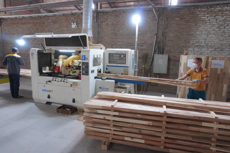 Two operators handling long boards at a moulder