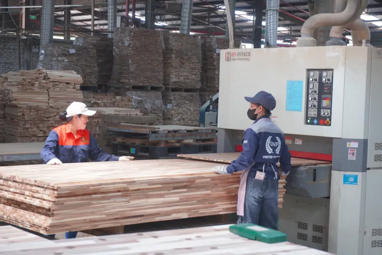 Two operators feeding a panel into a wide-belt sander